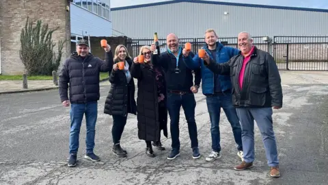 A picture of people standing outside the unit that I.T.S will use for its new facility.