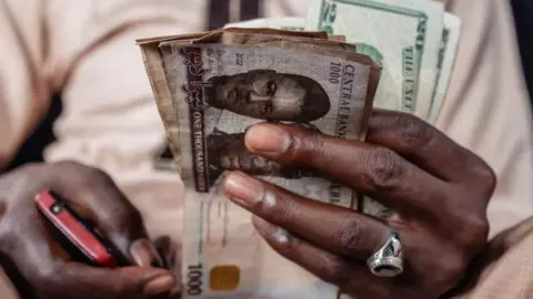 Nigerian man holding Naira and dollar currencies