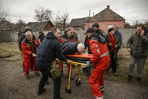 Getty Images Paramedics evacuate an injured elderly woman after a cluster bomb strike in Kramatorsk