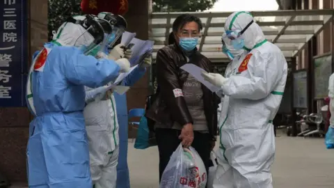 Getty Images Medical staff check information as patients infected by the COVID-19 coronavirus leave from Wuhan No.3 Hospital to Huoshenshan Hospital in Wuhan in China's central Hubei province on March 4, 2020.