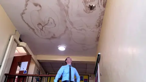 Holy Family School Principal John McCormack examining a leak in the school roof