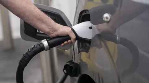 PA Media Somebody plugging their electric vehicle in to charge