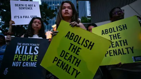 Getty Images Activists in Kuala Lumpur hold placards during a vigil in February 2025 against the execution of a Malaysian national sentenced to death for drug trafficking into Singapore