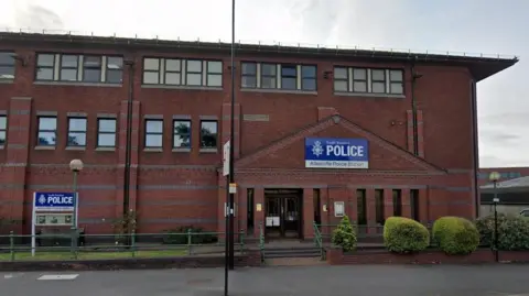 Google Attercliffe Police Station in Sheffield, with South Yorkshire Police signage, green railings and bushes.