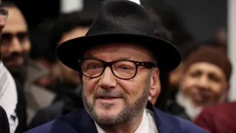 Reuters George Galloway, leader of the Workers Party of Britain wears a black felt fedora, raybans and a navy blazer. 