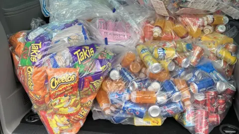 BBC Clear bags containing American Cheetos crisps, Takis, Fanta, Mountain Dew and other drinks which were seized from a shop by Trading Standards.