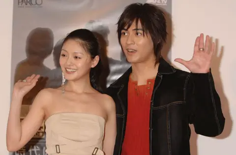 Getty Images Hsu and Vic Chou standing side by side and raising their hands at an event in Tokyo