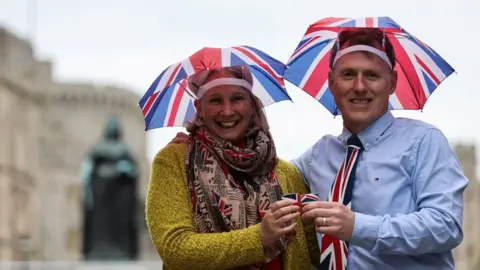 Getty Images A man and a woman wear umbrella hats with the flag of England