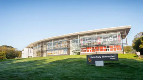 The image shows the modern Canterbury Innovation Centre building at University of Kent campus.