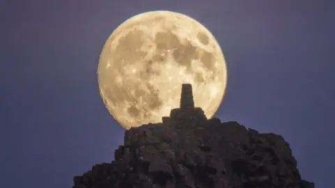 The supermoon rising behind Manstone Rock on The Stiperstones in Shropshire