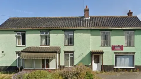 Green-coloured two-storey house with long thin windows