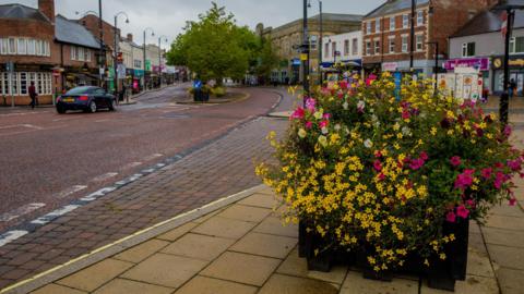 A road in Chester-le-Street with planter of yellow and pink flowers