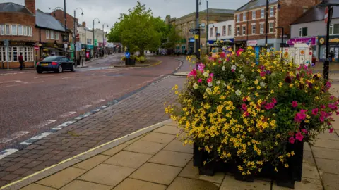 BBC A road in Chester-le-Street with planter of yellow and pink flowers