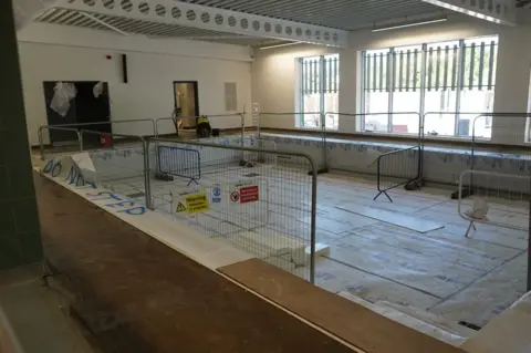 Wychavon A swimming pool with tape and railings around it and warning signs as it is under construction. 