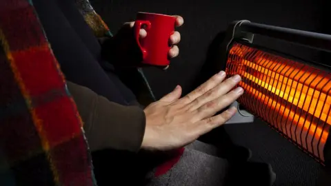 Getty Images man warms hands by fire