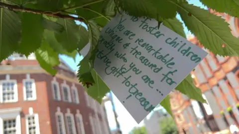 A message hung on a tree at the fostering event which says: "Foster children. You are remarkable, unique and treasured for exactly who you are...true gift to treasure!" 