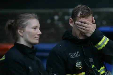 Getty Images Firefighters wait outside Grenfell Tower