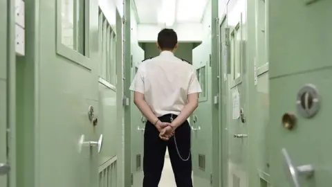 Rear view of a prison officer in a prison corridor