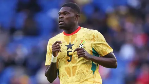 Thomas Partey running, wearing a yellow patterned Ghana shirt