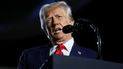 US President Donald Trump is seen standing at a podium behind a microphone