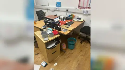 A smashed drawer and various items scattered on the laminate floor on Sunderland Mind in Hendon following one of the break-ins. The desk is covered in paper and there is a Union Jack flag across it.