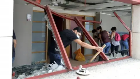 EPA Lebanese young people clear glass debris at the Al-Roum hospital in the aftermath of a massive explosion at Ashrafieh area in Beirut, Lebanon, 6 August 2020