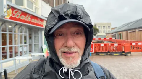 Andrew Turner/BBC Lee Ray with a grey beard and a black hood over his head and tied under chin with white cord