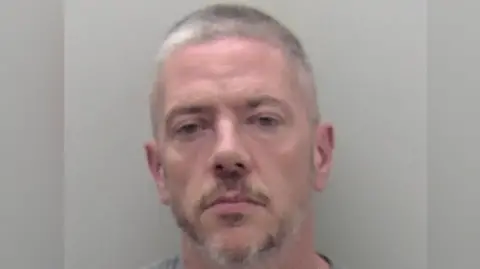 A man with short grey hair and beard. 