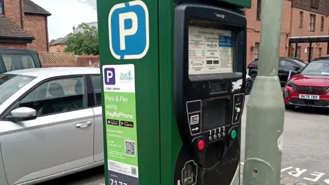 A parking machine with a QR code on the side of it