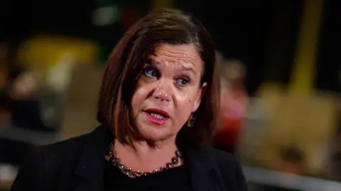 PA Mary Lou McDonald spoke in an interview.  He was wearing a dark jacket and shirt.