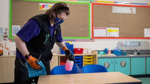 PA Media A member of staff disinfects tables at a primary school