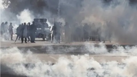 Reuters Supporters of former Prime Minister Imran Khan, react amid tear gas smoke, fired by the police to disperse them during clashes ahead of an election campaign rally, in Lahore, Pakistan (March 8, 2023).