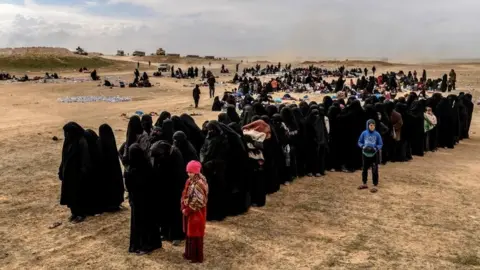 AFP Civilians evacuated from the Islamic State (IS) group's embattled holdout of Baghuz wait at a screening area held by the US-backed Kurdish-led Syrian Democratic Forces (SDF), in the eastern Syrian province of Deir Ezzor, on March 5, 2019