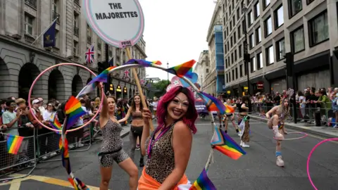 Reuters A woman with a hoop covered in LGBT flags poses for a photo in the middle of the Pride parade. Behind her are others from her group performing with hoops.