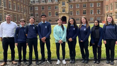 Northgate High School Seven pupils in blue school uniforms with two adults in a Cambridge court