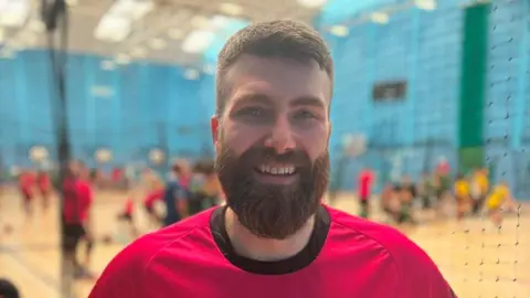 Anthony Aldred of Dodgeball Scotland, wearing the team's pink uniform, courtside at Aberdeen Sports Village