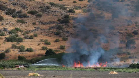 Os bombeiros da EPA apagam um incêndio que eclodiu como resultado de projéteis disparados do sul do Líbano, perto de Kfar Szold, no norte de Israel, 11 de outubro de 2024