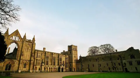 Exterior of Newstead Abbey, an ornate building with a green lawn and driveway at the front.