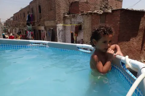 EPA A child holds on to the edge of temporary swimming pool in the Manshiyat Naser, a poor area of Egypt's capital city, Cairo.