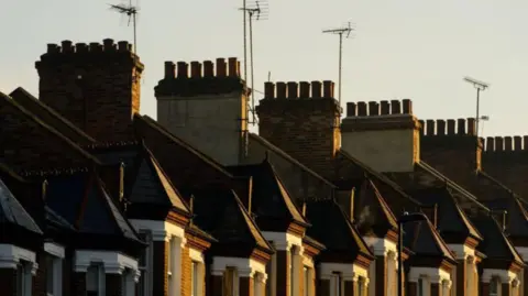 Half a dozen chimneys along with TV aerials are visible above upper floors of properties.