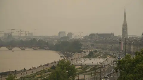 AFP via Getty Images Brown-tinged image of the city of Bordeaux, over which visible thick smoke has darkened the sky