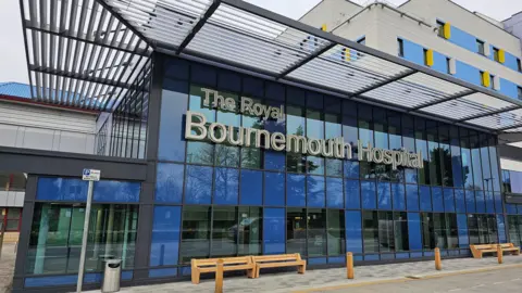 University Hospitals Dorset NHS Foundation Trust The new front entrance of Bournemouth hospital with a blue glass entrance building.