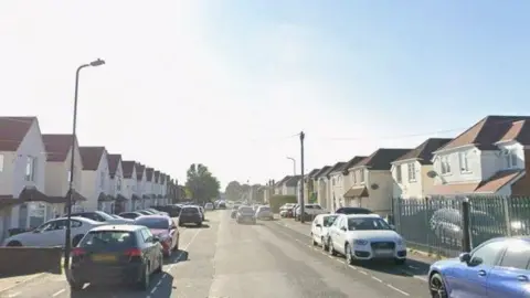 Google A Google Street View of a residential road with rows of houses on each side.