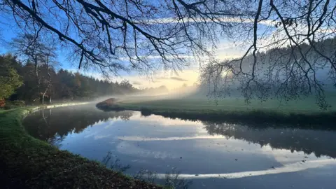 Just in Kinver / BBC Weather Watchers A wide canal looping around a field in Kinver. A mist hangs low over the water and the field on the far bank. Branches reach towards the water, above the photographer
