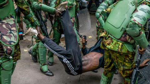  Kenyan police officers intervene in people during a protest against the tax hikes in planned Finance Bill 2024 as they march to the parliament building in Nairobi, Kenya on June 27, 2024
