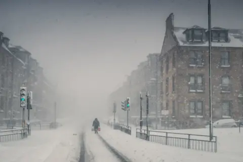 Neil Barr A lone figure walks through a blizzard