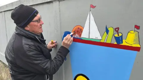 Retired teacher Chris Cowie painting a mural to cover graffiti tags in Edinburgh