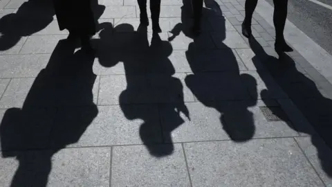 Getty Images Shadows of people walking on a pavement