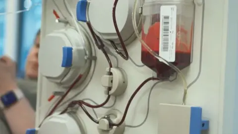 NHS Blood and Transplant A machine that takes plasma with a woman in the background donating