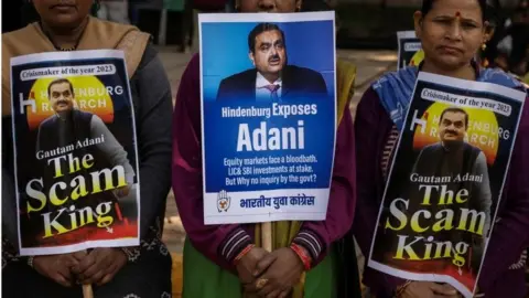 Reuters Activist of the youth wing of India"s main opposition Congress party hold placards featuring Gautam Adani, Chairman of Adani Group, during a protest against what they say are investments by Life Insurance Corporation (LIC) and State Bank of India (SBI) in Adani Group, in New Delhi, India, February 6, 2023.